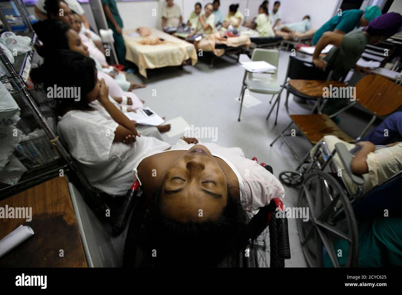 A pregnant woman reacts to contractions while sitting with other 