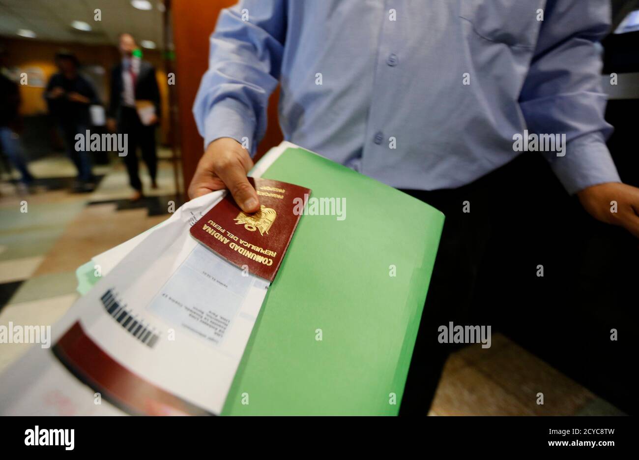 A man, holding a Peruvian passport and documents, participates in a visa  application demonstration during a media tour at the consular section of  the Embassy of the United States in Lima October