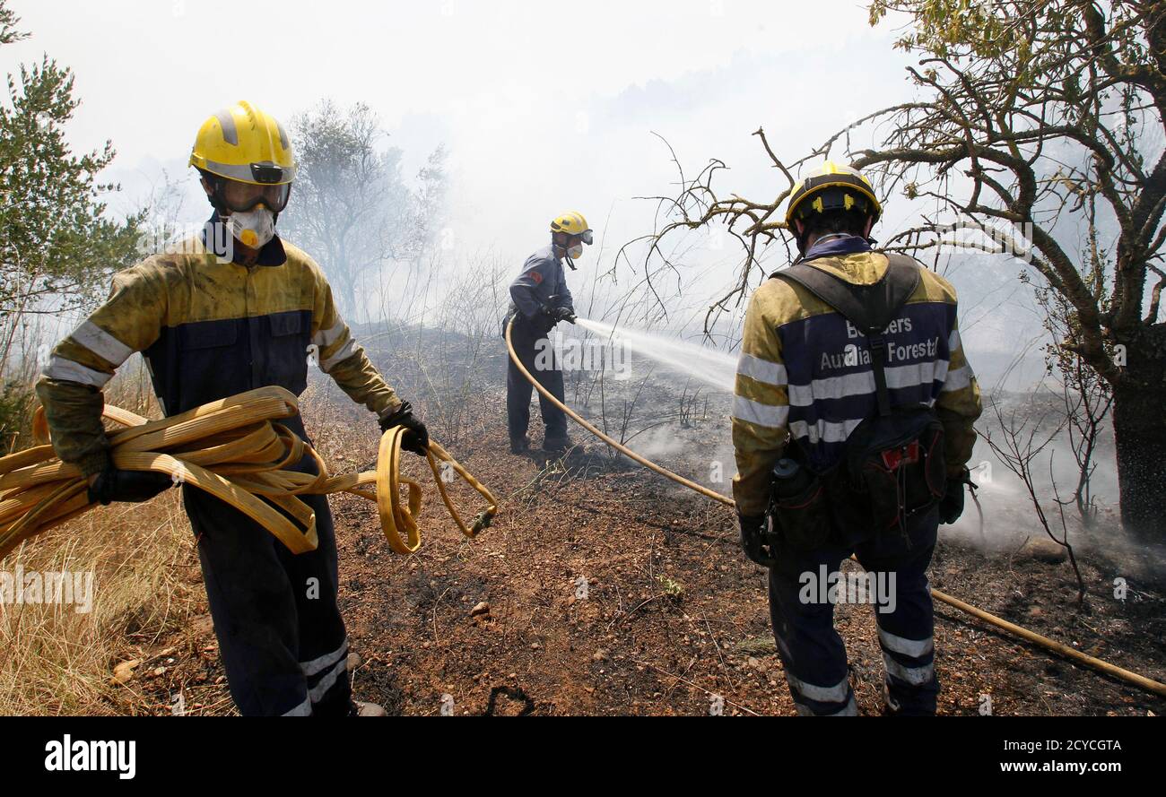 Firefighters extinguish flames near Llers, at the Spanish province of Girona July 23, 2012. Two big forest fires raging in the border area between France and northern Catalonia in Spain since Sunday have killed a fourth person, local authorities said on Monday, as strong winds hindered efforts to control the blaze. REUTERS/Albert Gea (SPAIN - Tags: DISASTER ENVIRONMENT) Stock Photo