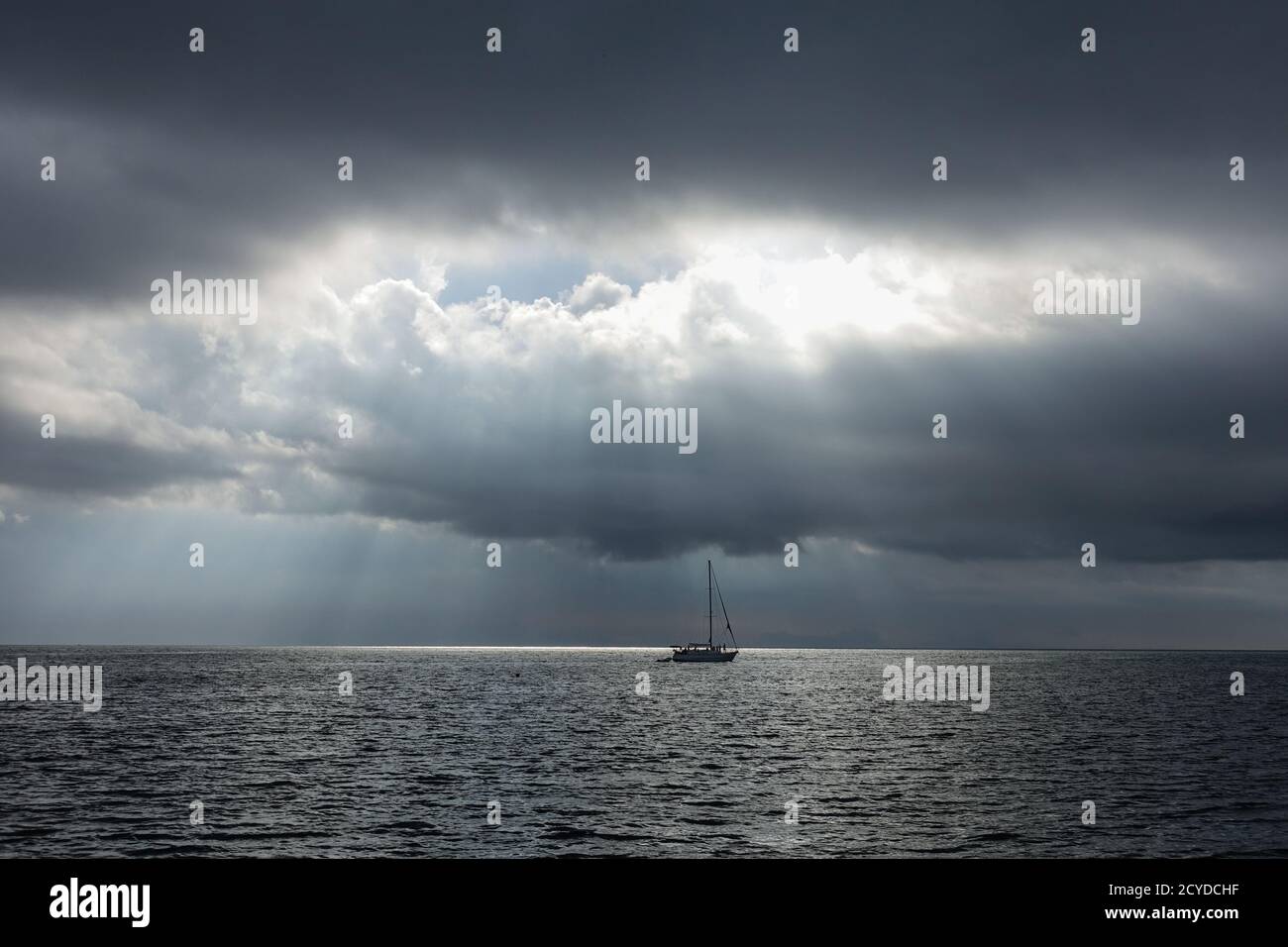 Sailboat in the dark sea, only a few rays of light illuminate the sea COLOMBIA Stock Photo