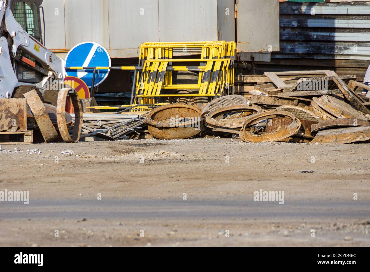 bulk of old manhole wellsold manholes of wells piled in a heap, next to temporary road signs and emergency barriers Stock Photo