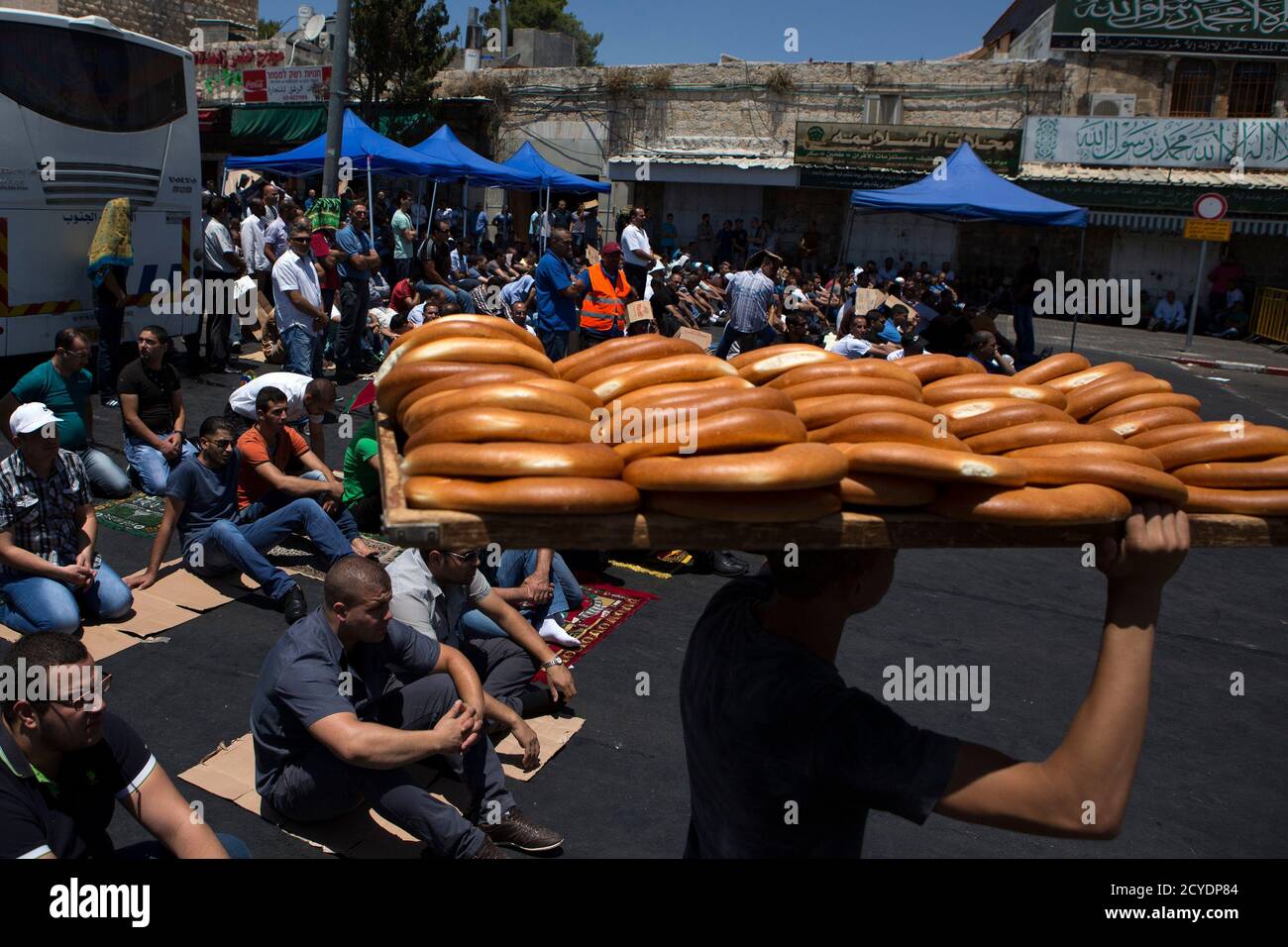 A youth walks by carrying loaves of bread as worshippers prepare to pray on the last Friday of the holy month of Ramadan close to the Damascus Gate of the Old City in Jerusalem July 25, 2014. REUTERS/Siegfried Modola (JERUSALEM - Tags: RELIGION FOOD) Stock Photo