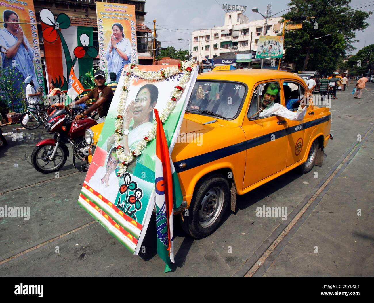 A man drives an iconic yellow ambassador taxi with a portrait of Trinamool Congress party leader Mamata Banerjee attached to the front in a street in Kolkata, May 13, 2011. India's ruling Congress-led coalition overturned three decades of communist rule in the swing state of West Bengal on Friday, one of several regional poll victories that could give some respite for a beleaguered Prime Minister Manmohan Singh. The Congress alliance led by maverick populist Mamata Banerjee was leading in 215 seats out of the 294 at stake in the West Bengal state assembly, with the communists ahead in 72 seats Stock Photo