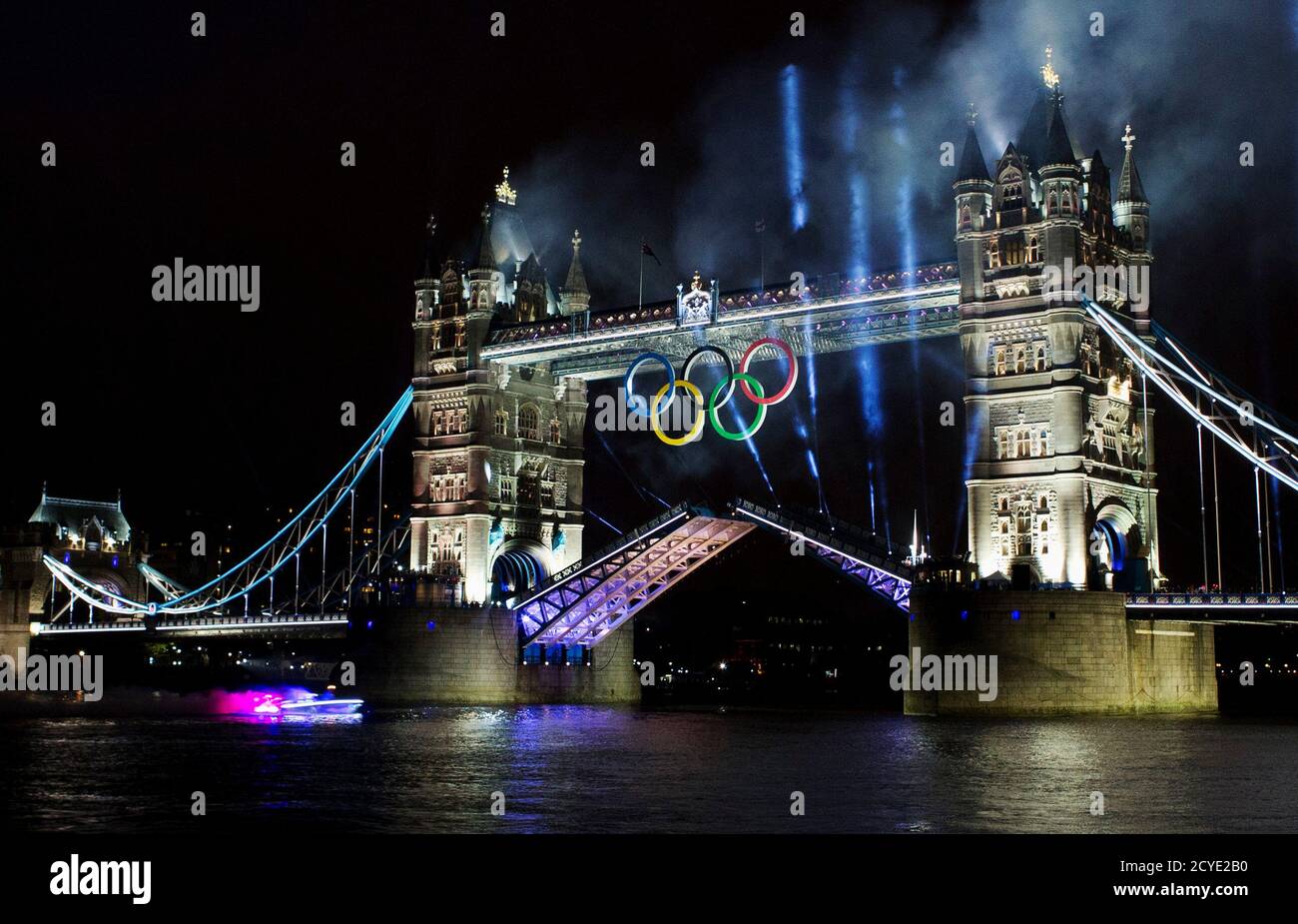 A speedboat carrying footballer David Beckham holding the Olympic torch, races under the Tower Bridge during the opening ceremony of London 2012 Olympic Games July 27, 2012. REUTERS/Mark Blinch (BRITAIN - Tags: SPORT OLYMPICS) FOR BEST QUALITY IMAGE SEE:GM2E88E1KDC01 Stock Photo