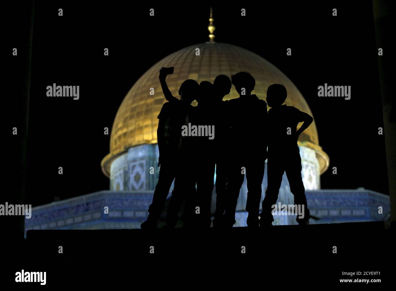 Palestinian Ali Souwan, 12, from the West Bank city of Hebron, takes a selfie photo with his friends in front of the Dome of the Rock on the compound known to Muslims as Noble Sanctuary and to Jews as Temple Mount, in Jerusalem's Old City, during the holy month of Ramadan, July 4, 2015. Souwan said he has not been to Al Aqsa in three years, and that he took the selfie to show his friends and so that he'll have a souvenir. Palestinians young and old have jumped on a trend for taking 'selfies' at Al Aqsa, the 8th century Muslim shrine in Jerusalem, both as a personal memento and for relatives pr Stock Photo