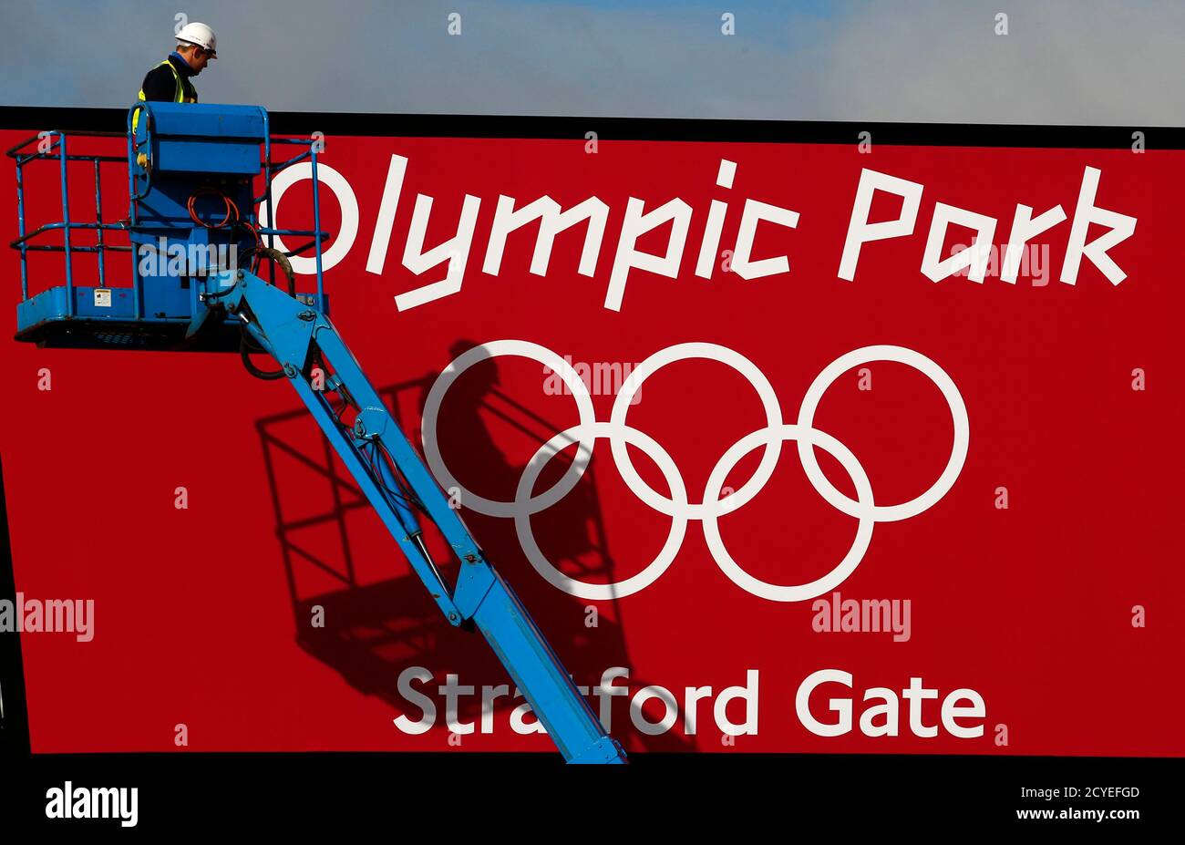 A worker adjusts his position on a cherry picker in front of one of the signs at the entrance to the Olympic Park, Stratford, east London, July 19, 2012. The 2012 London Olympic Games will begin in just over a week.  REUTERS/Andrew Winning (BRITAIN - Tags: SPORT OLYMPICS) Stock Photo