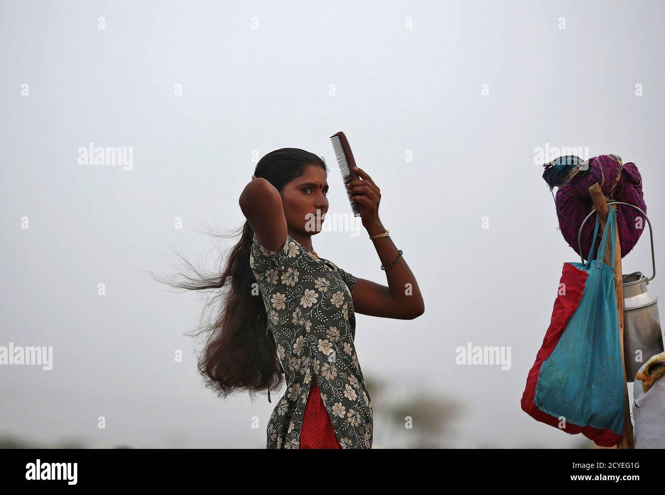 A village woman combs her hair after she migrated due to shortage of water  on the outskirts of Sami town in the western Indian state of Gujarat August  6, 2012. Armed with