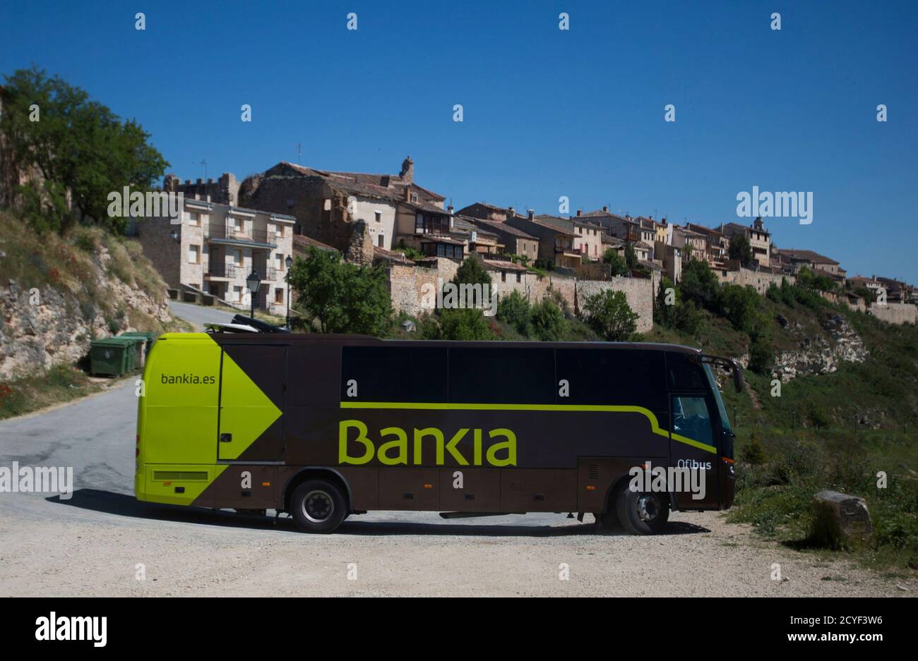 A travelling bank bus drives down the road after making its monthly call on  customers in the village of Maderuelo, central Spain, June 4, 2013. A queue  of pensioners waits to board