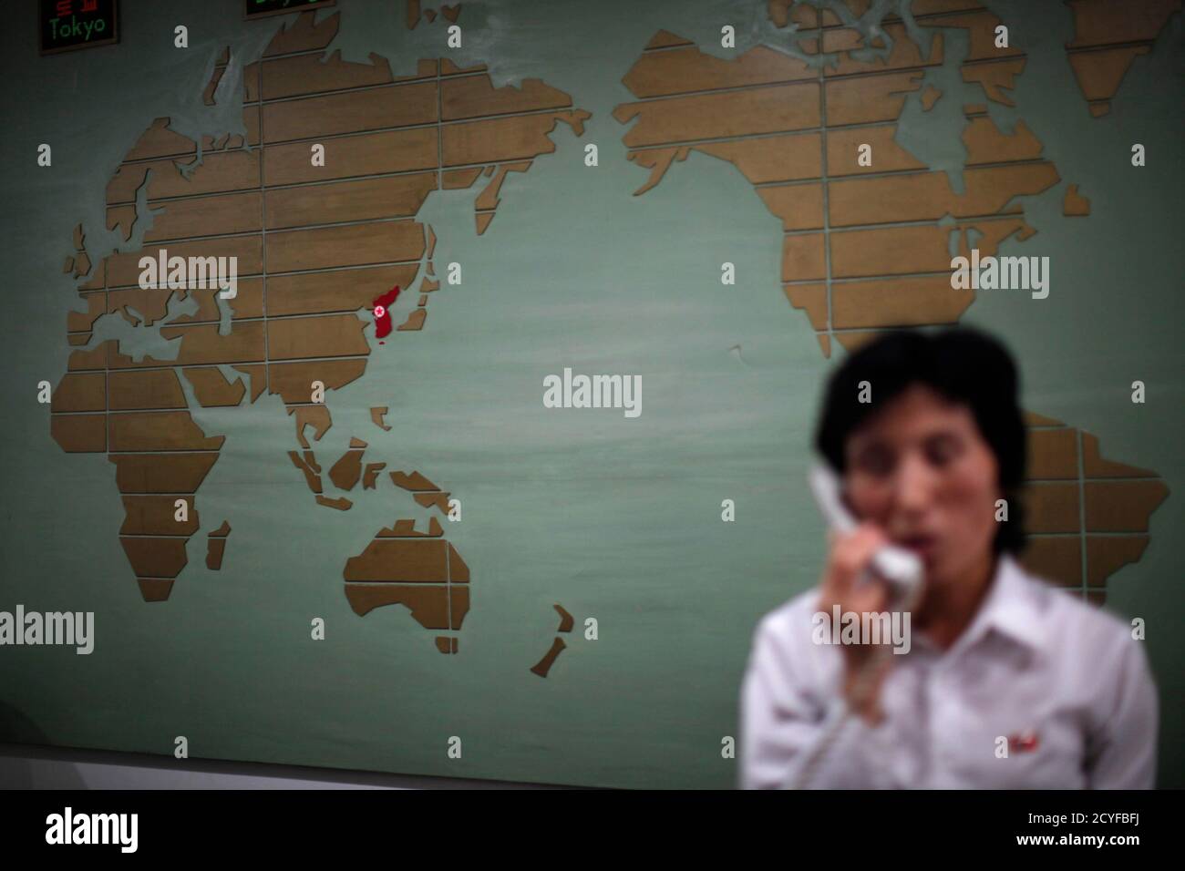 A world map, with the Korea peninsula marked in red, is seen as a hotel receptionist talks on the phone in Rason city, northeast of Pyongyang, August 29, 2011. REUTERS/Carlos Barria (NORTH KOREA - Tags: POLITICS TRAVEL TPX IMAGES OF THE DAY) Stock Photo