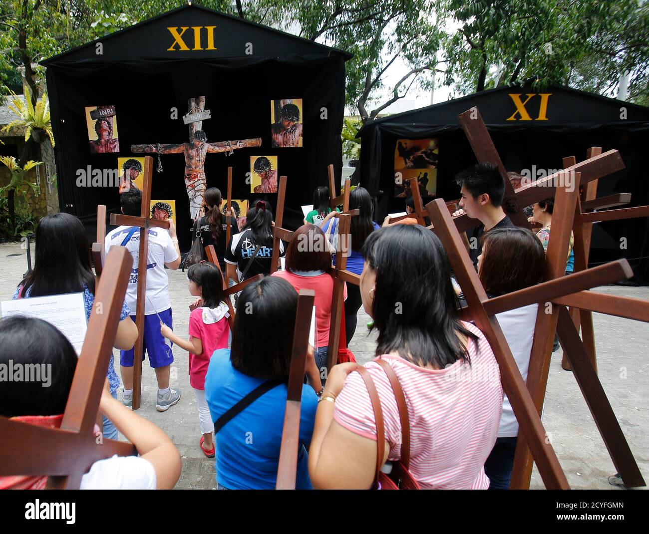 Catholic devotees carry crosses to one of the Stations of the Cross