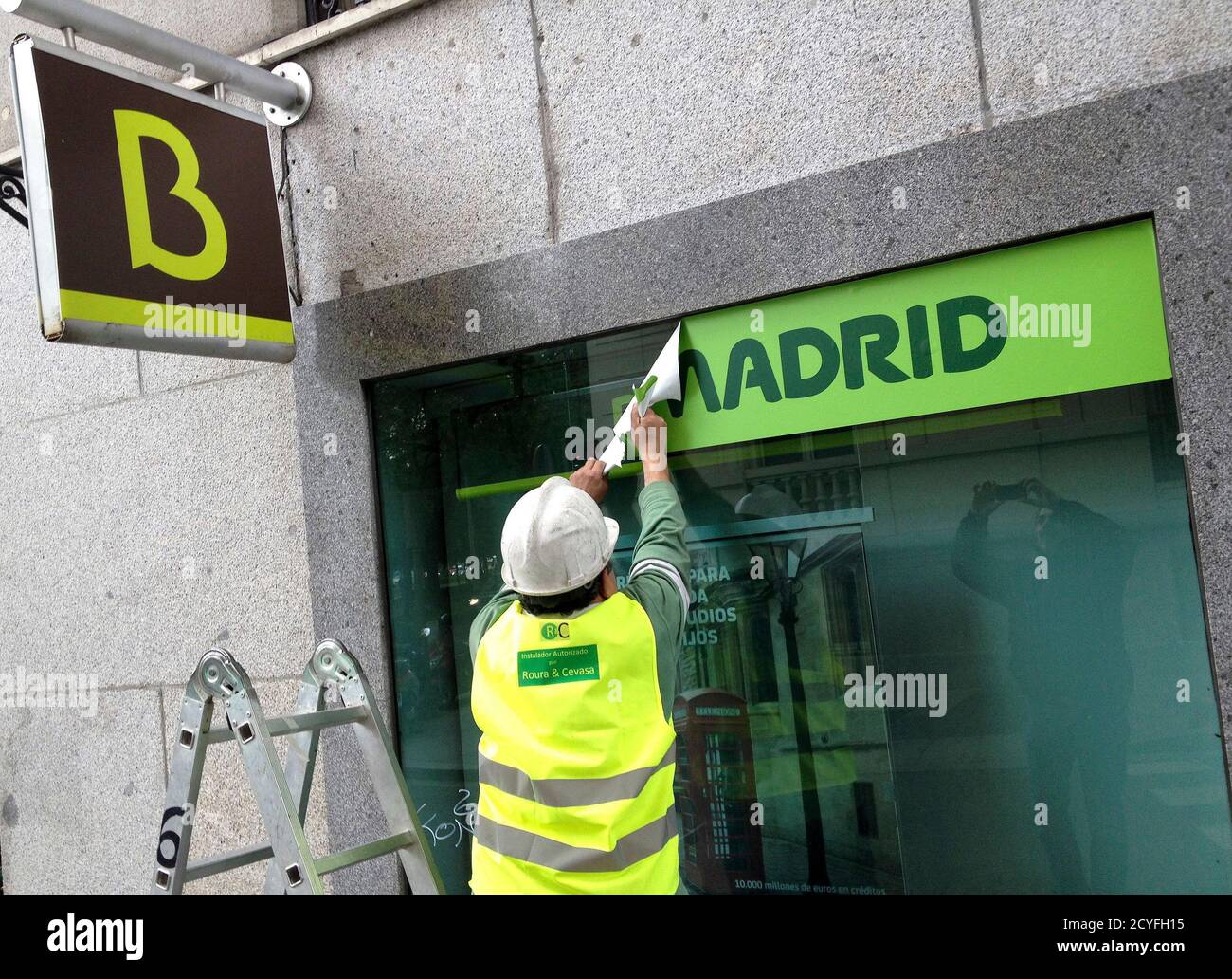 A worker removes a Caja Madrid signage to replace it with Bankia logos at a  Bankia branch in Madrid May 20, 2013. Many duped savers at Spanish lender  Bankia are shunning a