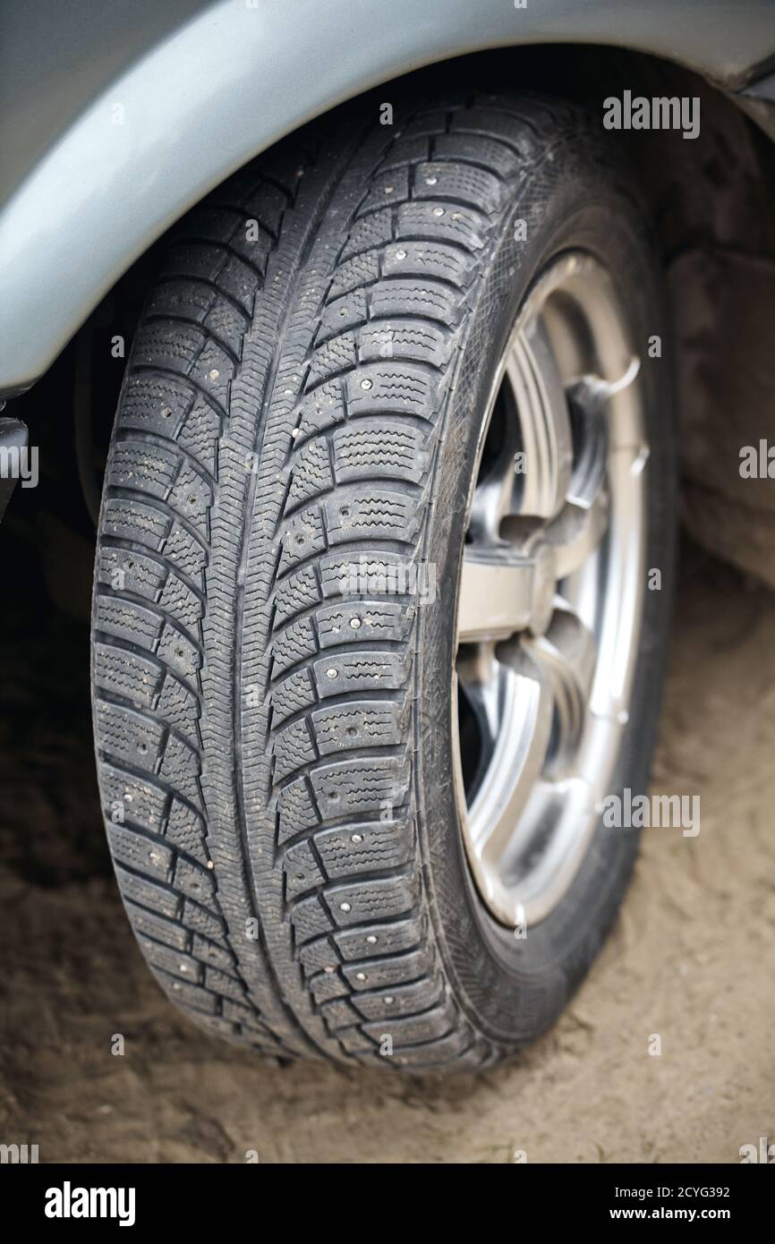 Used winter tire with metal studs closeup, some studs lost. Protector for winter studded tire. Lost spikes old rubber. Concept of accident risk cause Stock Photo