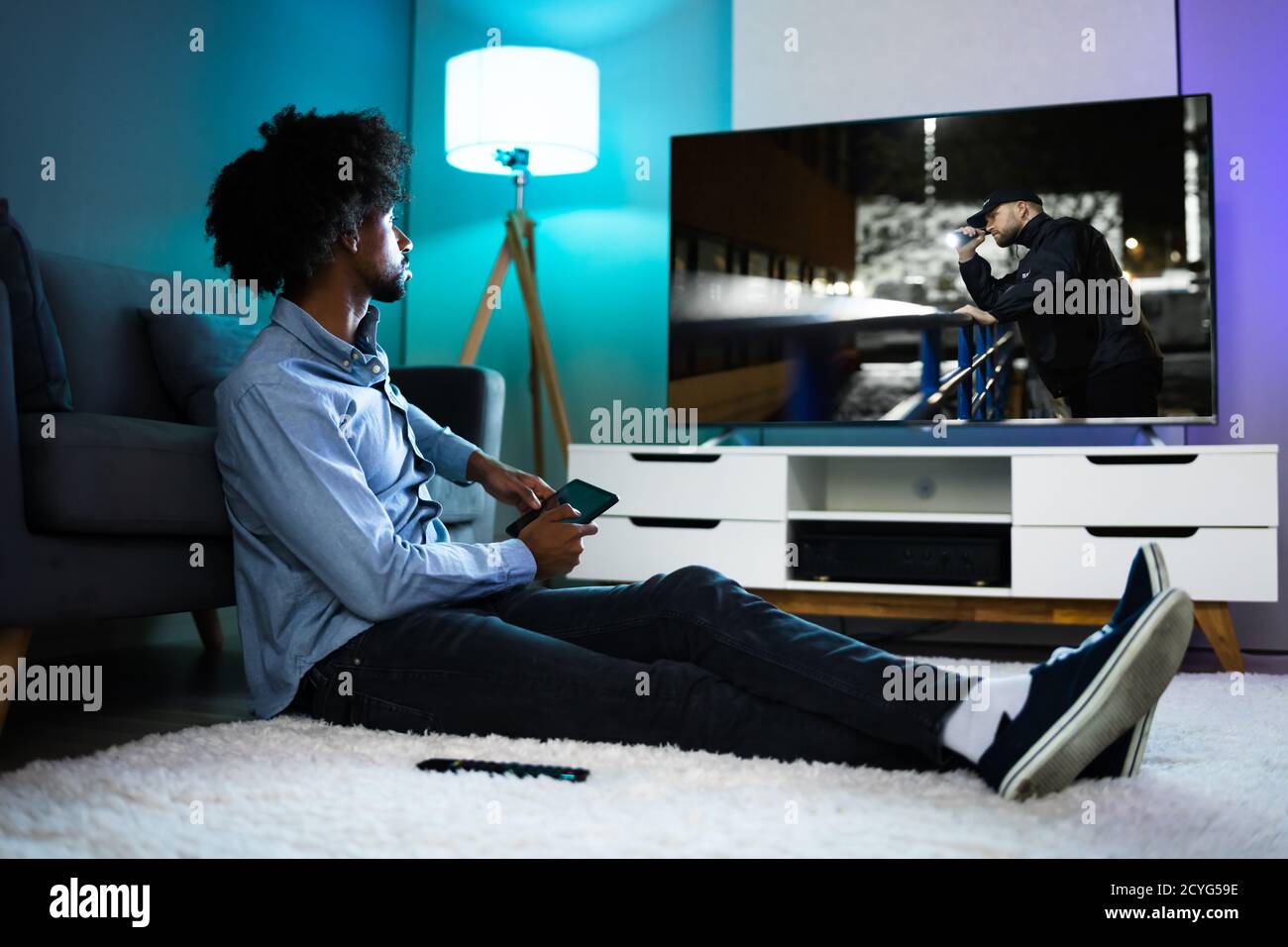 African Man Watching TV Movie Or Television Stock Photo