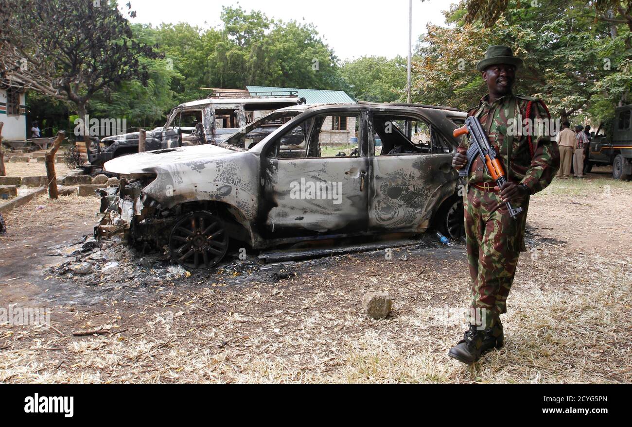 A policeman guards government cars burnt in the recent attack by unidentified gunmen in the coastal Kenyan town of Mpeketoni, June 18, 2014. Kenya's president shifted blame to domestic rivals on Tuesday for two attacks that killed 65 people on the coast and he dismissed claims of responsibility by Somali Islamist militants, which Nairobi usually fingers for such assaults. REUTERS/Thomas Mukoya (KENYA - Tags: SOCIETY CIVIL UNREST CRIME LAW TPX IMAGES OF THE DAY) Stock Photo
