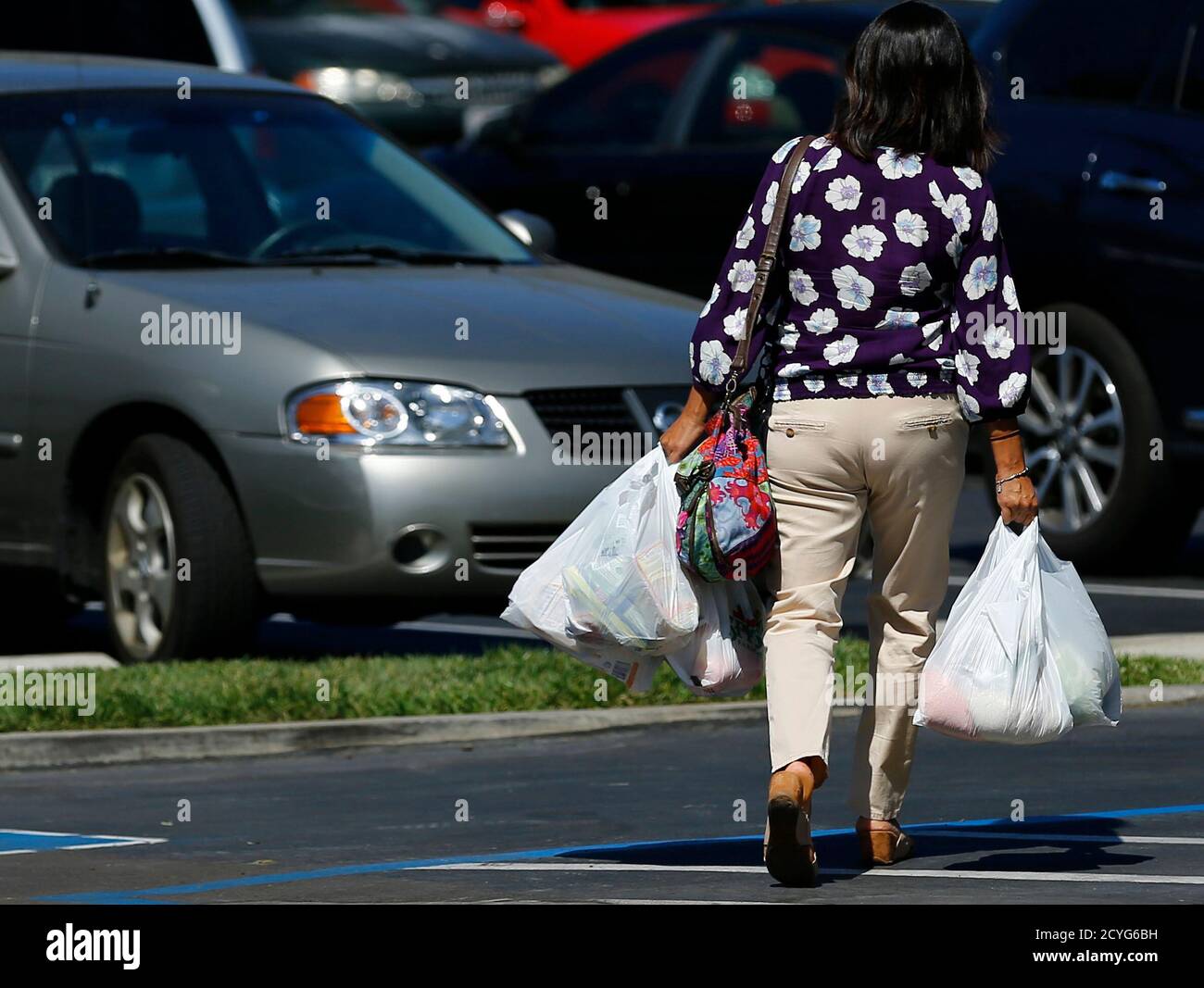A shopper carries her groceries to her car in plastic bags after shopping at a Sprouts grocery store in San Diego, California September 30, 2014. Single-use plastic bags are set to disappear from California grocery stores over the next two years under a first-in-the-nation state law signed on Tuesday by Democratic Governor Jerry Brown, despite opposition from bag manufacturers.      REUTERS/Mike Blake (UNITED STATES - Tags: BUSINESS ENVIRONMENT) Stock Photo