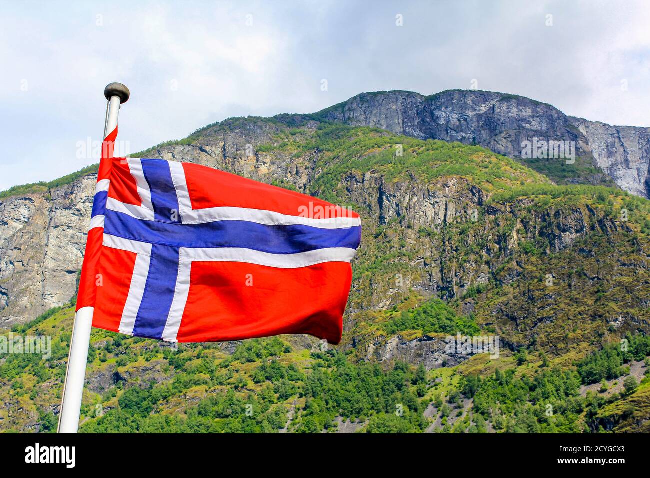 The national flag of Norway in the rough wind and blue sky with clouds ...