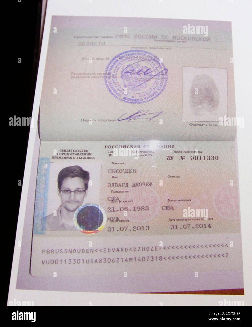 Fugitive former U.S. spy agency contractor Edward Snowden's new refugee  documents granted by Russia is seen during a news conference in Moscow  August 1, 2013. Snowden slipped quietly out of the airport