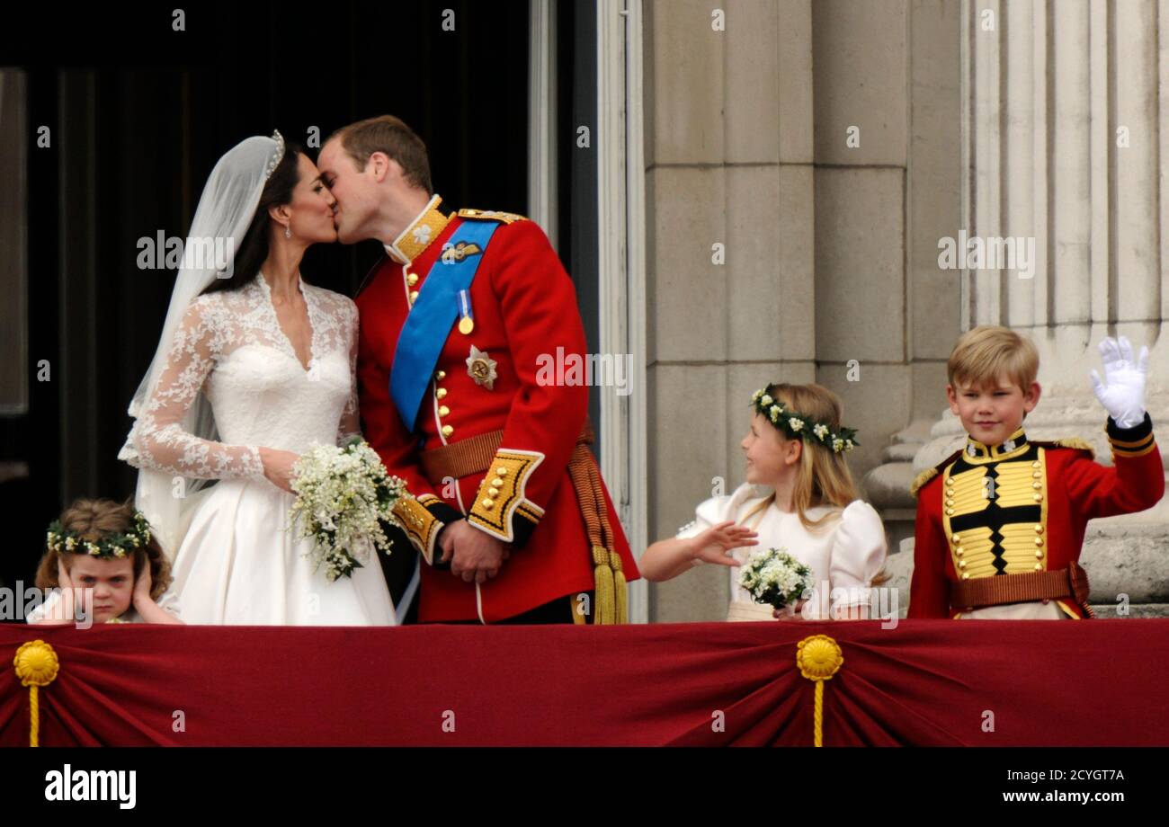 Britain's Prince William and his wife Catherine, Duchess of Cambridge kiss  on the balcony at Buckingham Palace, watched by bridemaids Grace van Cutsem  (L) and Margarita Armstrong-Jones and pageboy Tom Pettifer, after
