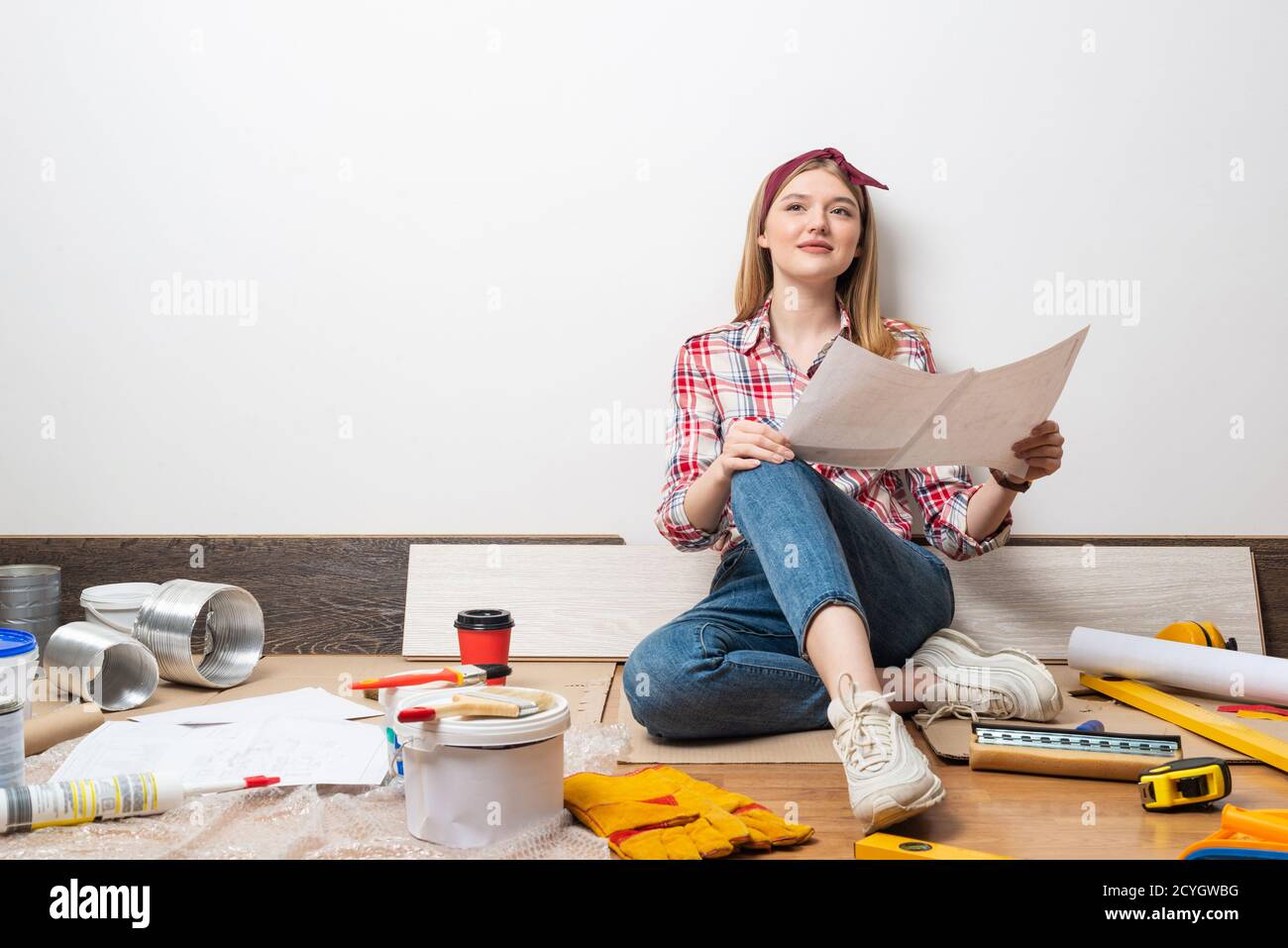 Smiling girl sitting on floor with blueprint Stock Photo - Alamy