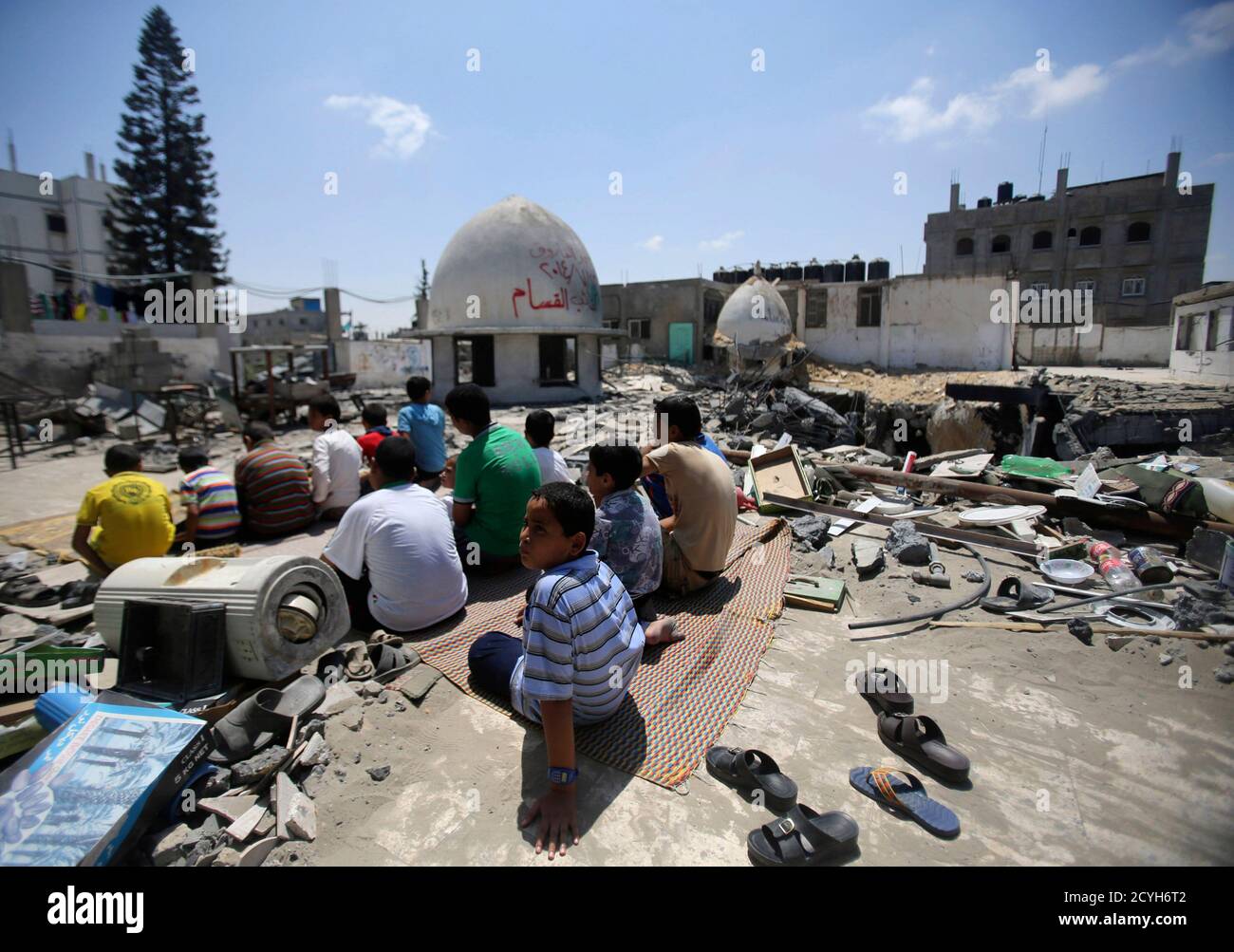 Palestinians perform Friday prayers among the ruins of a mosque, which witnesses said was hit by an Israeli air strike during the Israeli offensive, in Rafah in the southern Gaza Strip August 22, 2014.  Since the collapse on Tuesday of a 10-day ceasefire, the Israeli military has ramped up its efforts to hit the leadership of Hamas's armed wing, the Izz el-Deen al-Qassam Brigades. Israel launched its offensive in Gaza on July 8 with the declared aim of curbing Palestinian rocket fire into its territory. Hamas has said it will not relent until the Israeli-Egyptian blockade on the Gaza Strip is  Stock Photo