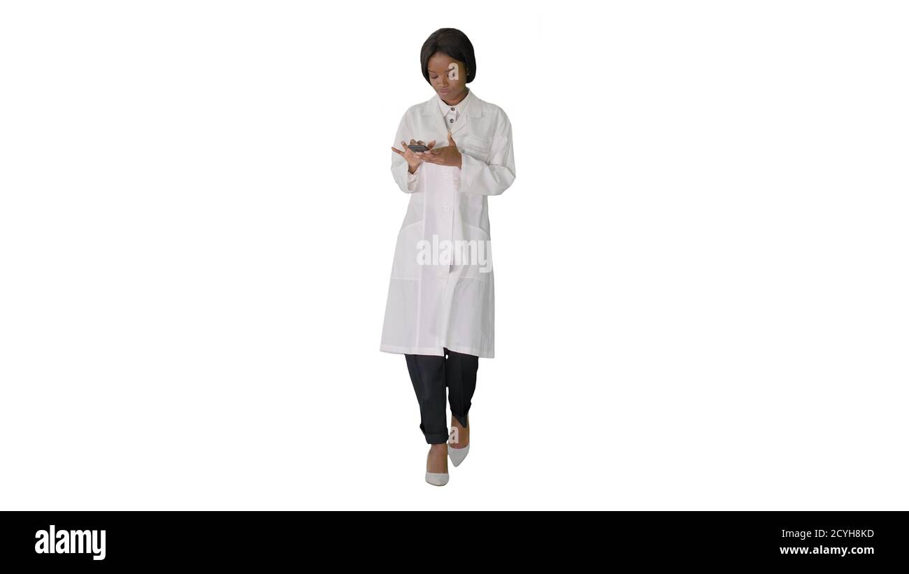 African American female doctor using phone while walking on whit Stock Photo