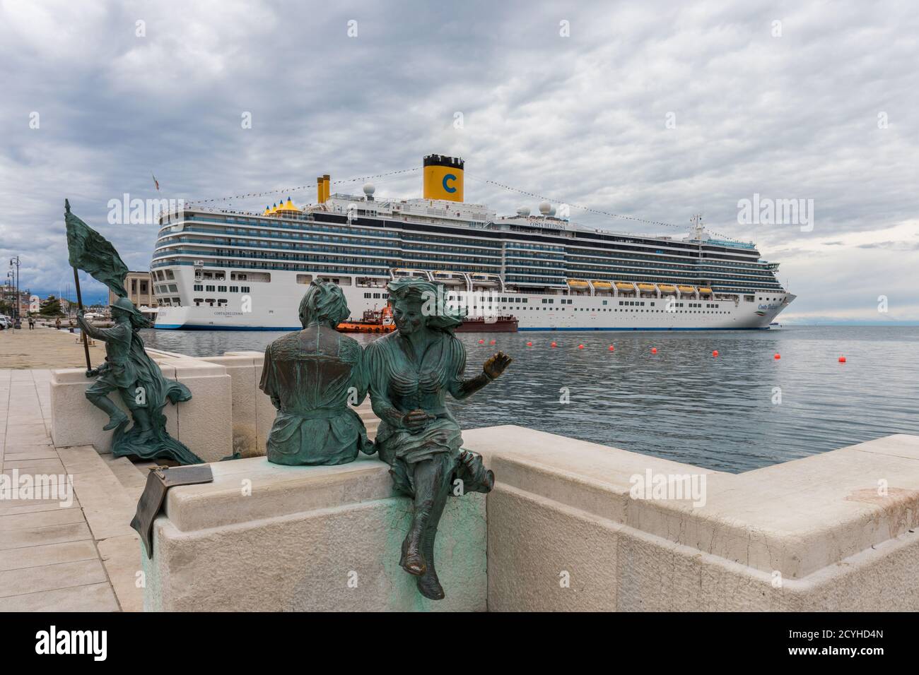 Luxury cruise ship Costa Deliziosa; Bersagliere monument and Le Sartine statue in the foreground - Trieste, Friuli Venezia Giulia, Italy Stock Photo