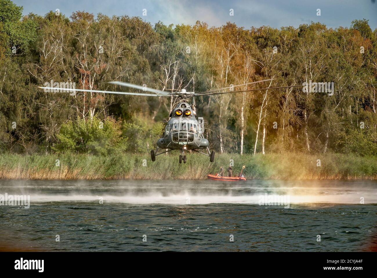 Military helicopter Mi-8 hovers motionless - straight view. You can see the water breeze from the blast of the helicopter and the hot air. Stock Photo