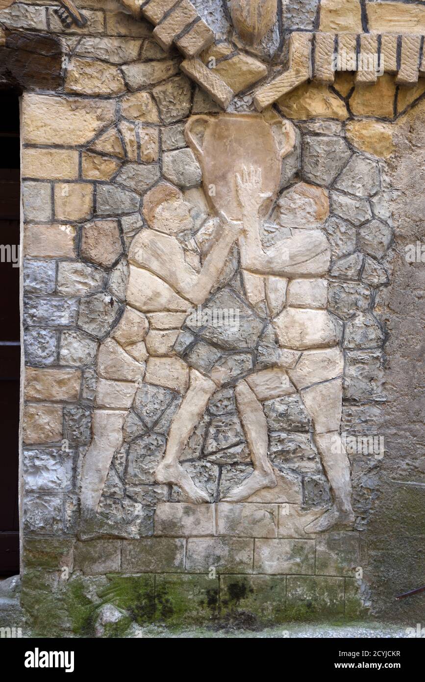 Folk Art Sculpture (c1970) of Two Men Collecting Rainwater in Water Jar from Roof Gutter System on Façade of François Barra House Annot Provence Stock Photo