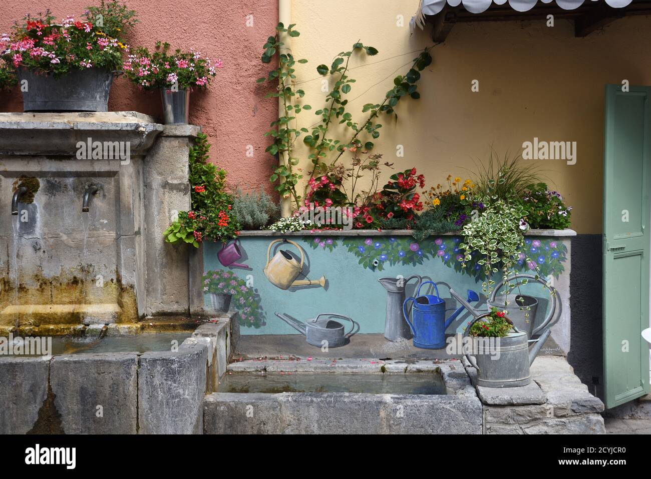 Trompe l'Oeil Decorative or Painted Village Fountain with Antique or Old Metal Watering Cans Colmars-les-Alpes Alpes-de-Haute-Provence Provence France Stock Photo