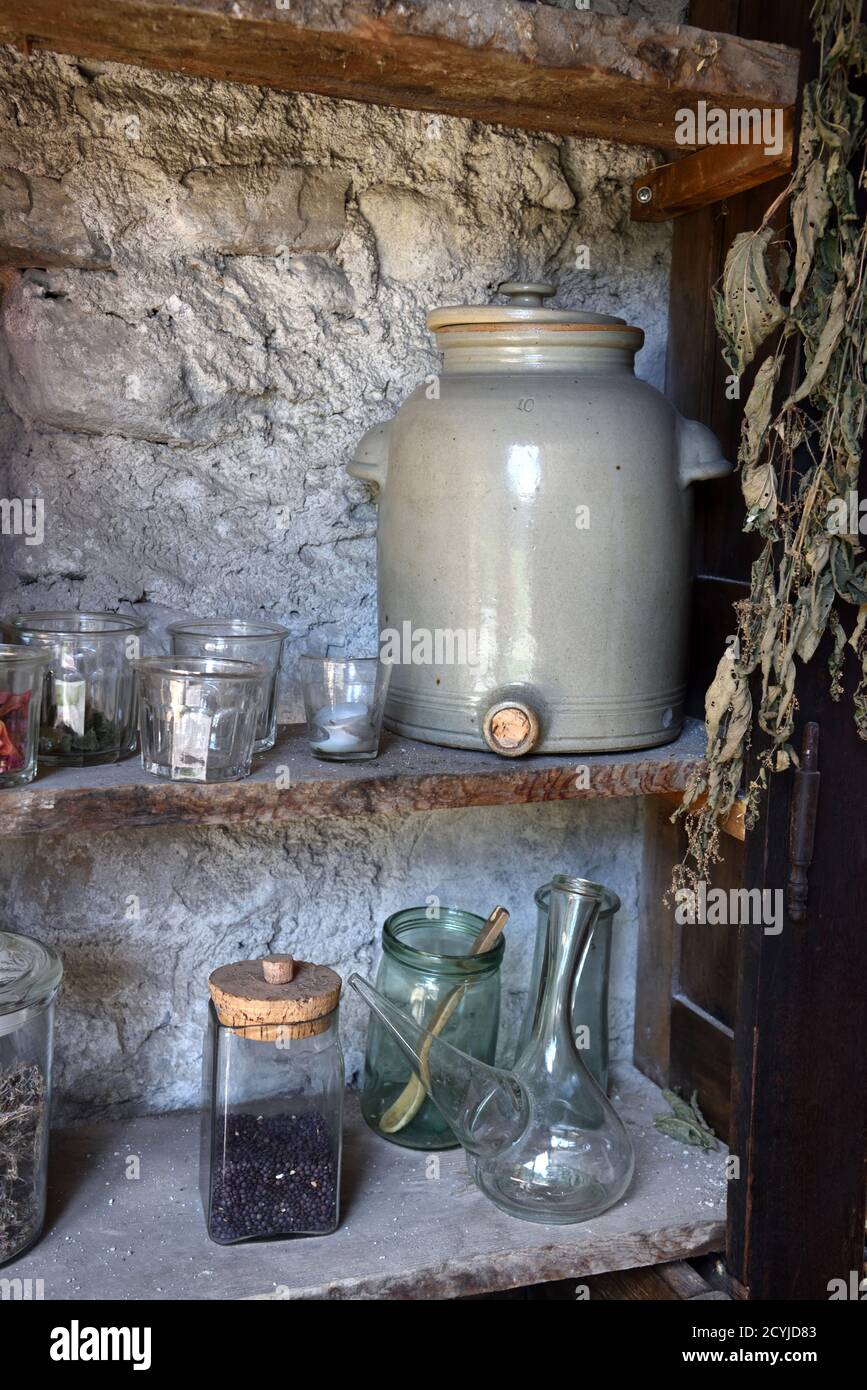 Vintage Wooden Shelves or Old Rustic Shelf, Glassware, Glasses, Storage Jars, Antique Earthenware Jar & Tap or Spigot Jar in Old Kitchen Interior Stock Photo