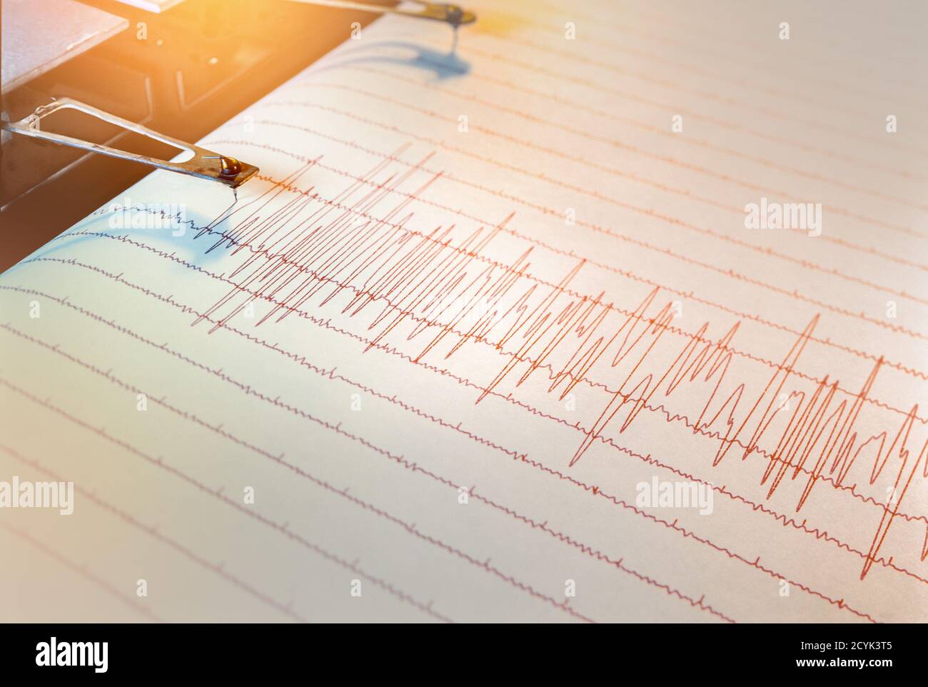 Swinging needle of seismograph at long lasting earthquake in back lit atmosphere. Stock Photo