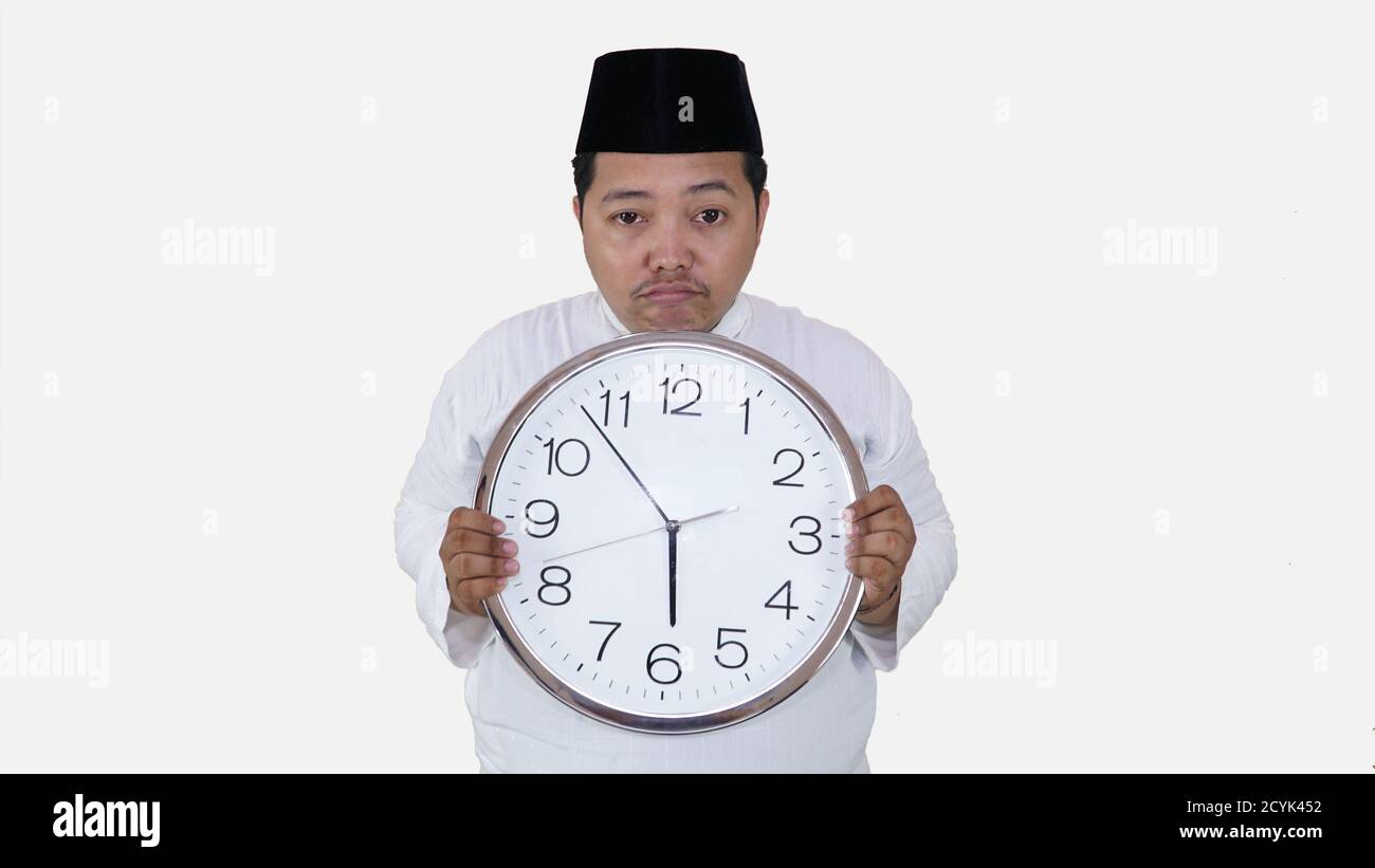 muslim asian with overweight standing and holding big round clock waiting for break fasting. islam fat boy can't waiting for muslim break fasting conc Stock Photo
