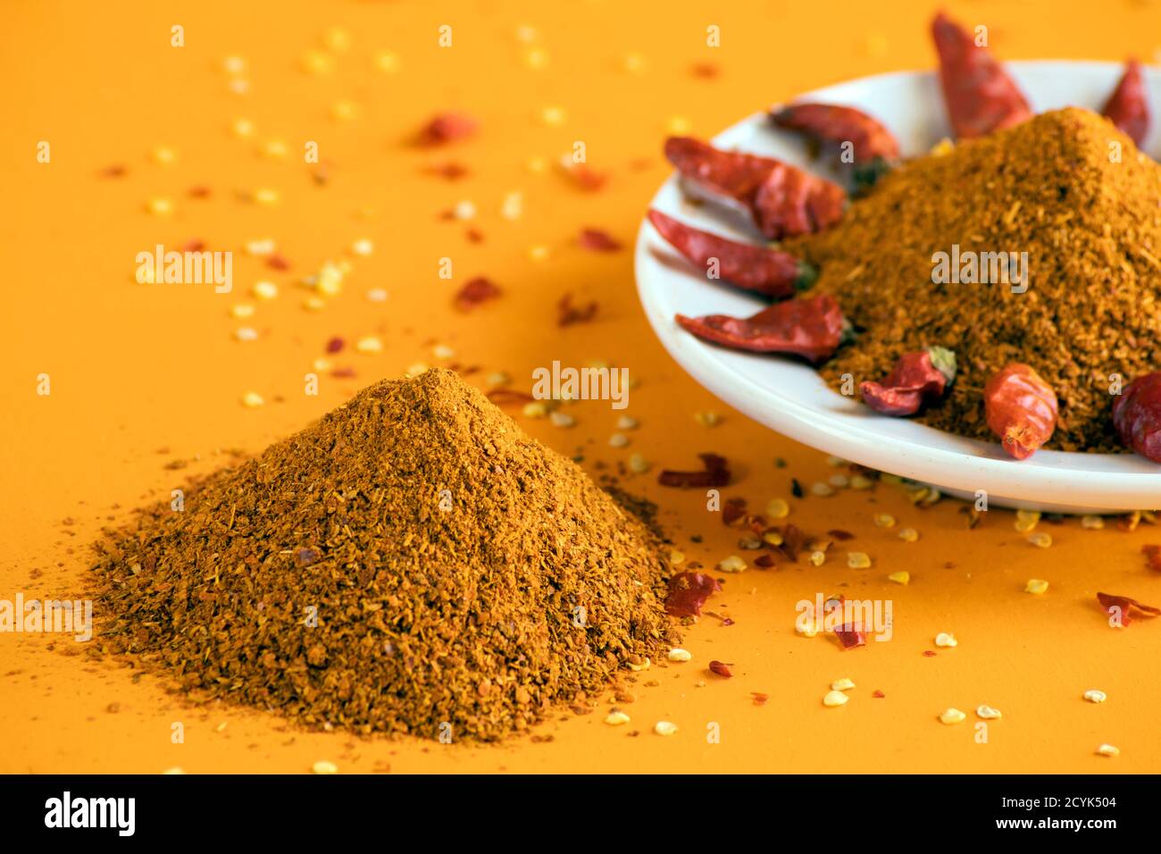 A pile of red cayenne chili powder and chili peppers on a white plate ...
