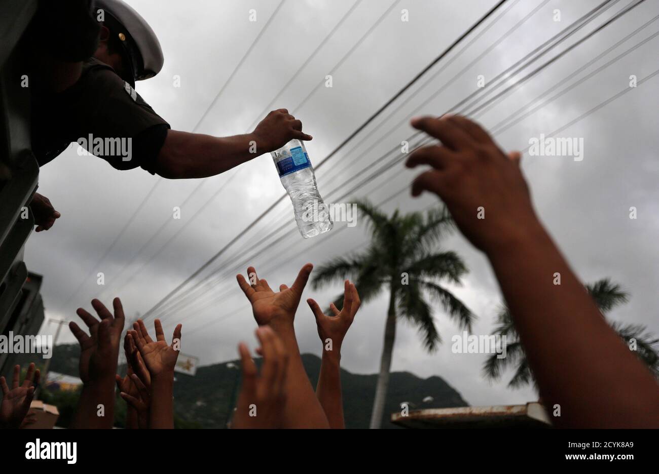 A soldier hands out bottled water to residents in Acapulco September 18, 2013. Looting broke out in the flooded Mexican beach resort of Acapulco on Wednesday as the government struggled to reach tens of thousands of people cut off by flooding that had claimed at least 80 lives. REUTERS/Tomas Bravo (MEXICO - Tags: DISASTER ENVIRONMENT MILITARY) Stock Photo