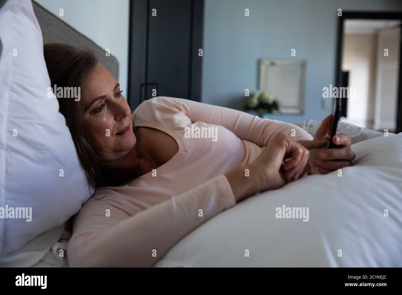 Senior woman using smartphone in bed at home Stock Photo