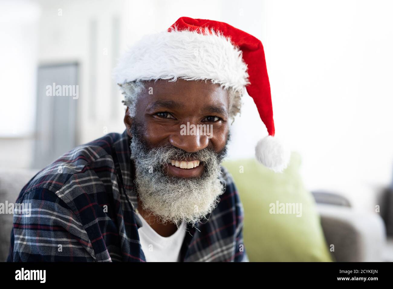 Portrait of man wearing santa hat smiling at home Stock Photo