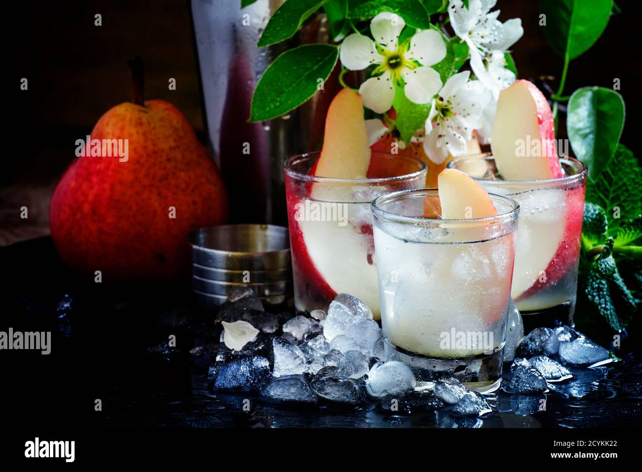 Alcoholic cocktail with pear, vodka, sprite, crushed ice and lime juice, black background