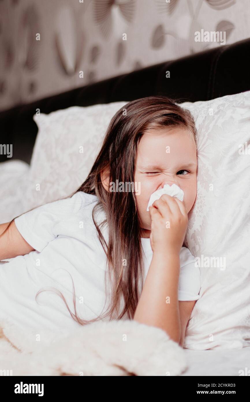 the child is lying with a swollen red nose from a runny nose, a cold and a second wave of the virus Stock Photo