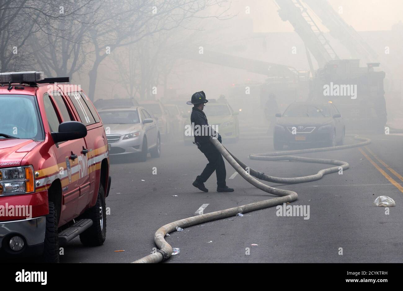 Fire fighter pulls hoses on East 116th street near an apparent building  explosion fire and collapse in the Harlem section of New York City, March  12, 2014. A building collapsed in Upper