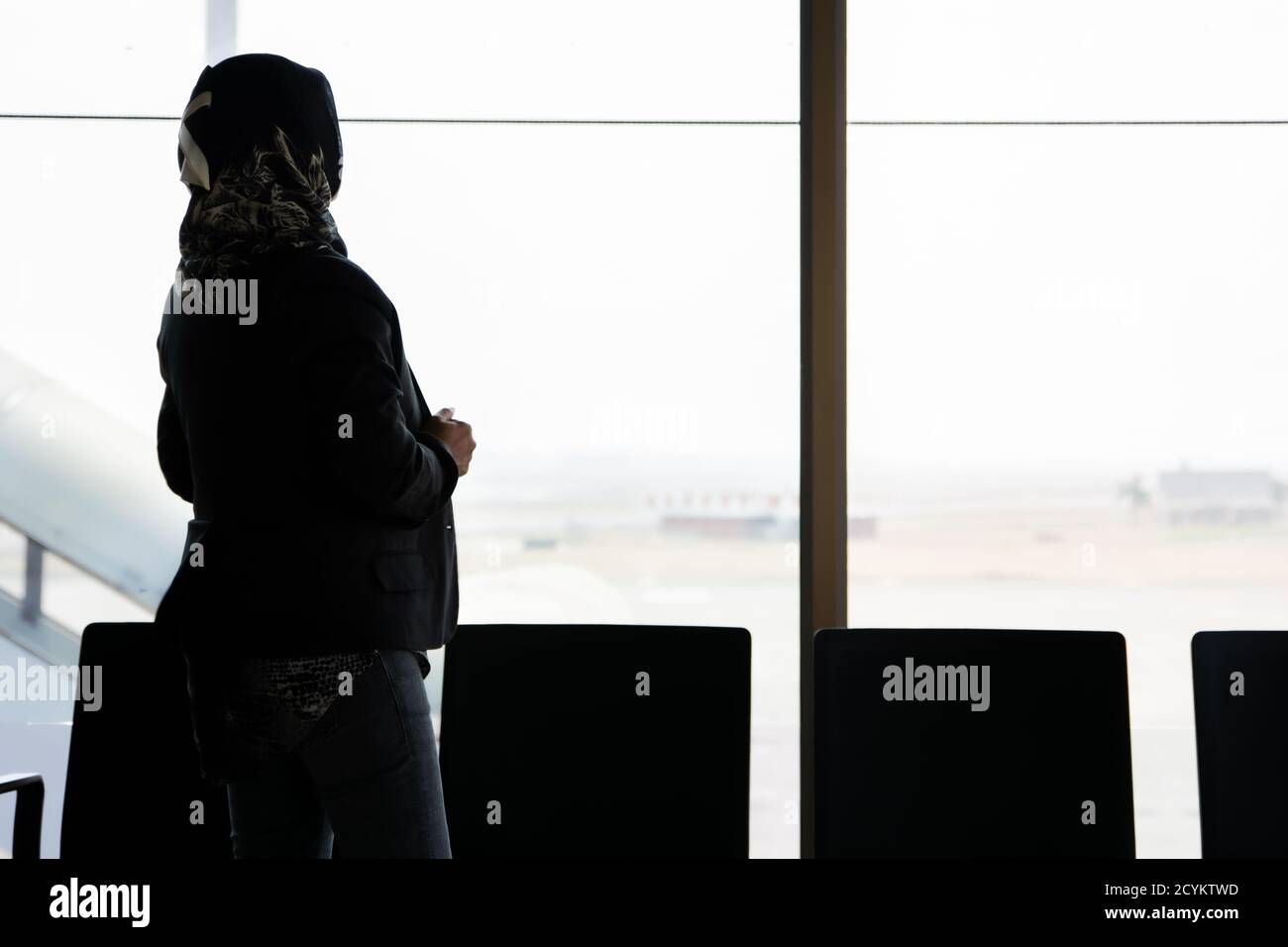 the silhouette of the rear view of a veiled Muslim woman standing in ...