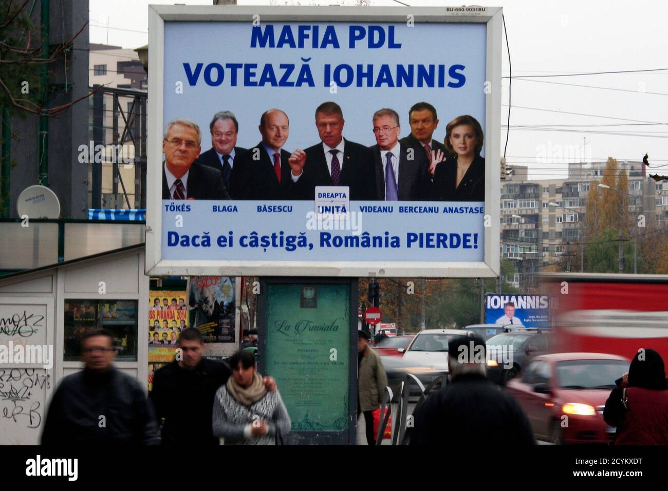 People walk past an electoral poster against Romania's presidential  candidate Klaus Iohannis (C) in Bucharest November 15, 2014. Romania's  leftist Prime Minister Victor Ponta is widely expected to win the  presidential election