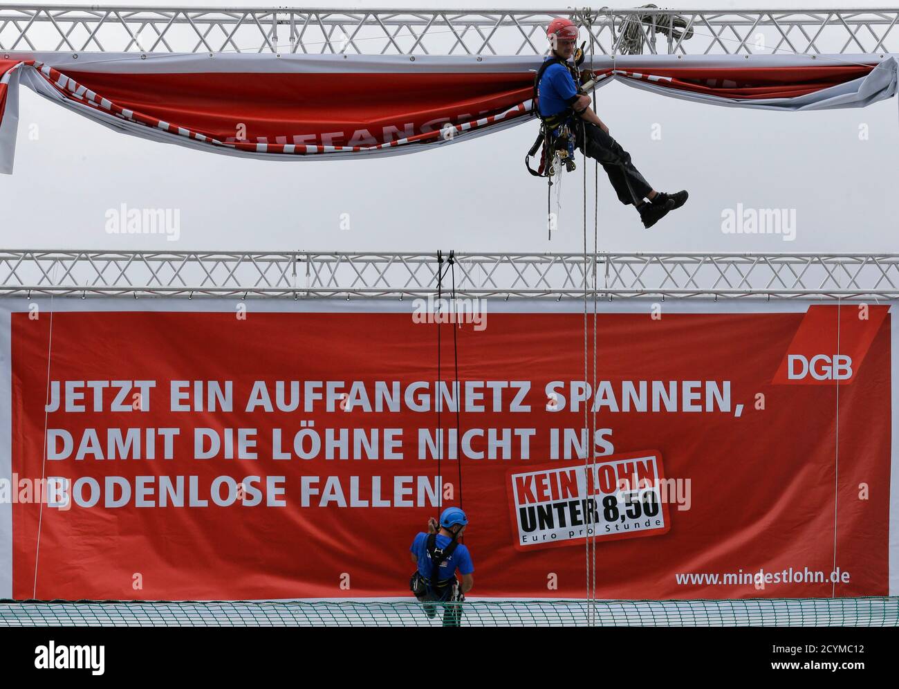 Climbers unveil a banner during a campaign of German labour union  association DGB calling for minimum wage of 8.5 euro per hour in Berlin  September 4, 2013. The banner reads: 'To stretch