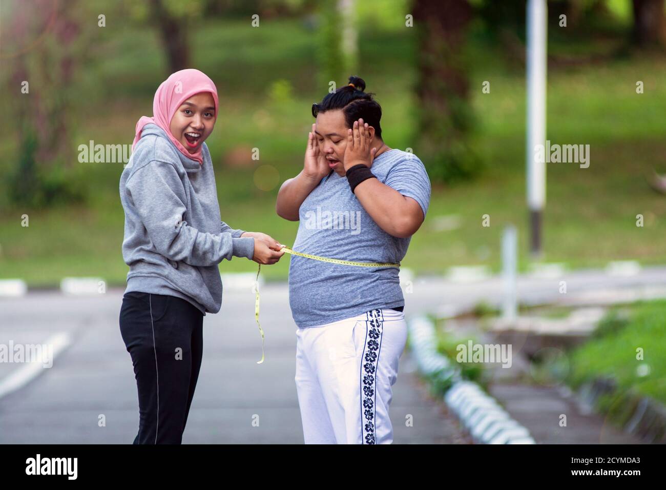 two-people-muslim-woman-and-fat-man-proportional-and-over-weight-comparing-themselves-by-measure-the-circumference-of-the-stomach-body-with-a-met-2CYMDA3.jpg