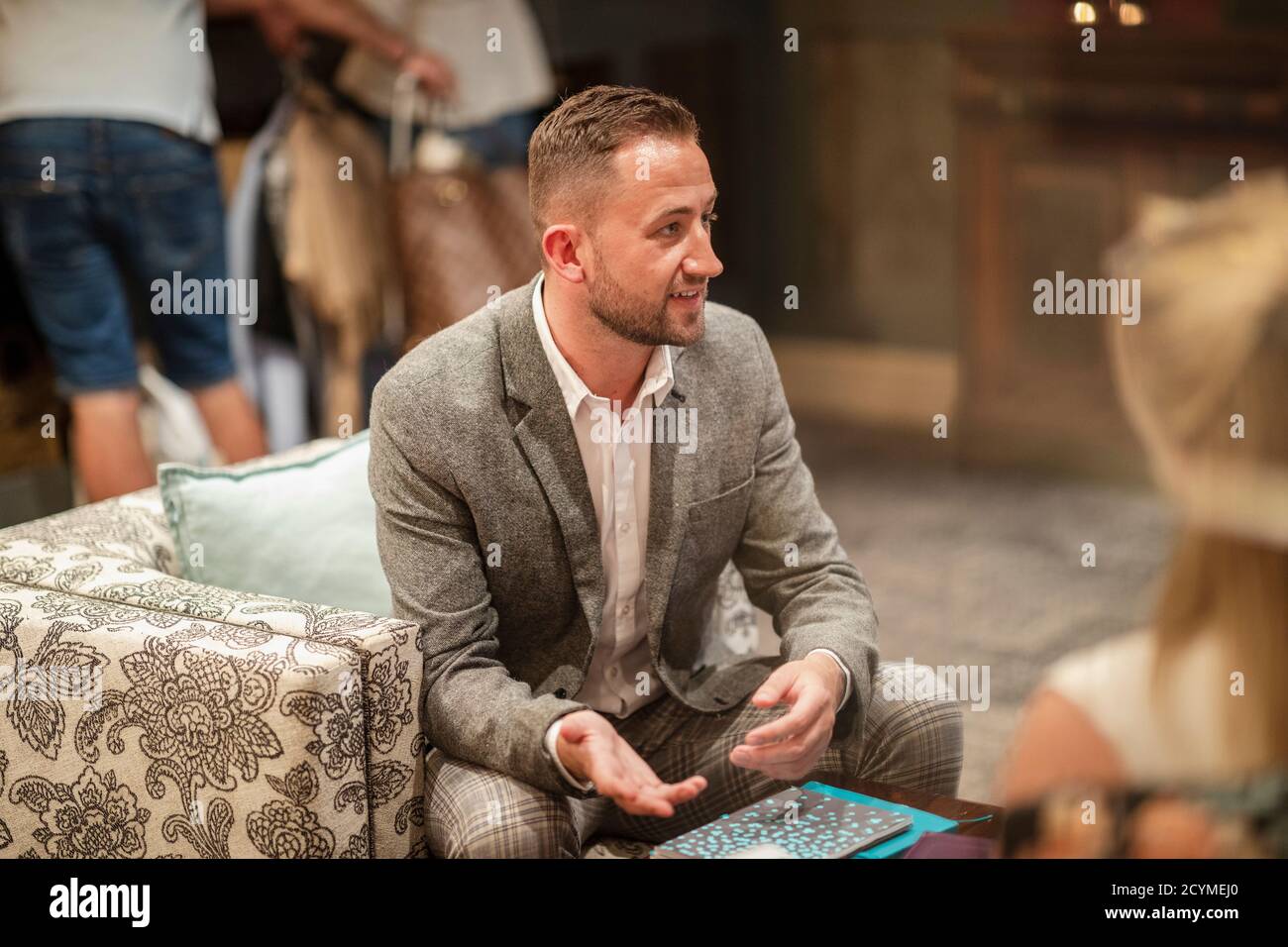 A shot of a businessman wearing smart clothing sitting in a lobby, he is talking business. Stock Photo