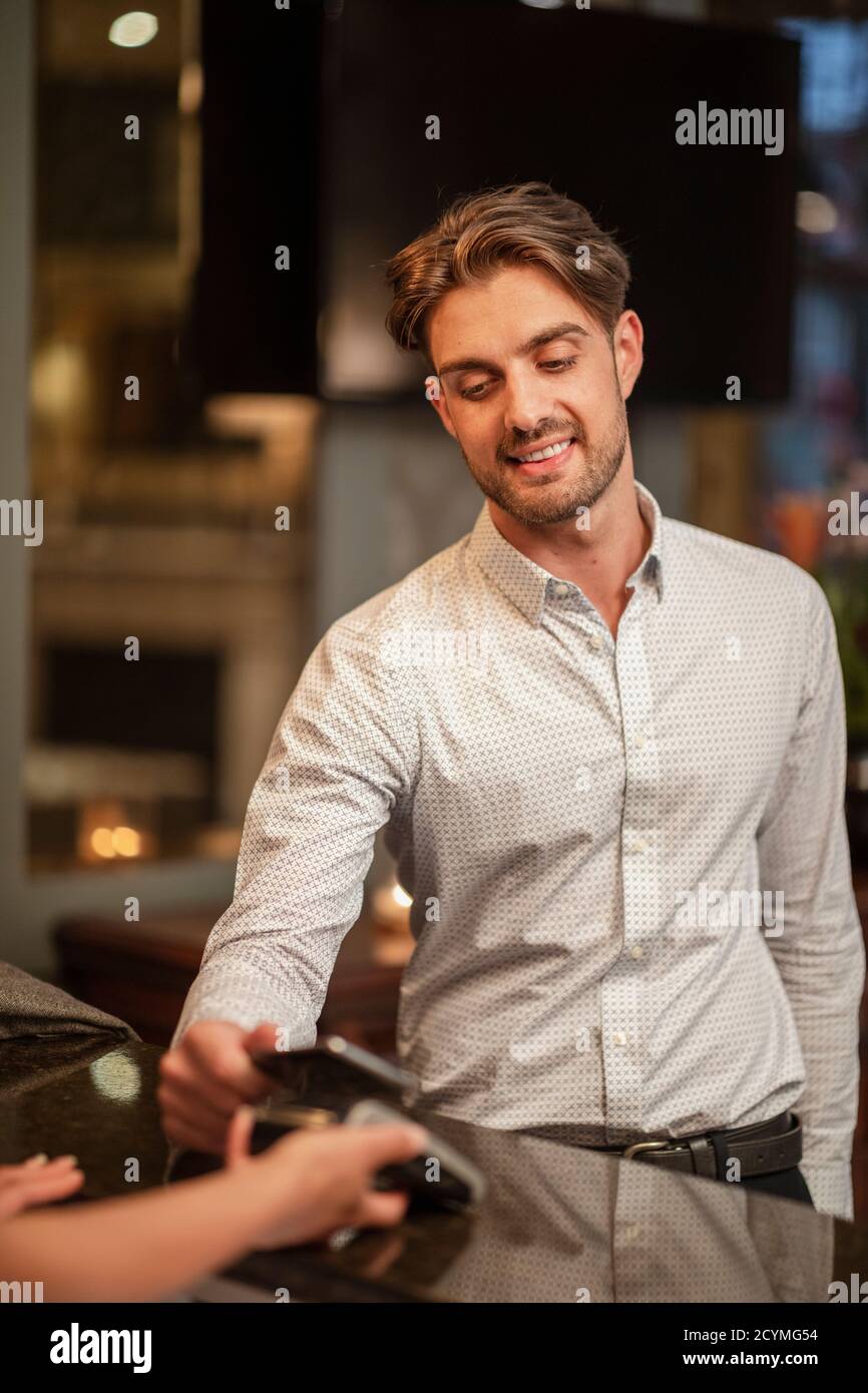 A man wearing smart clothing, he is making a contactless payment with his smart phone. Stock Photo