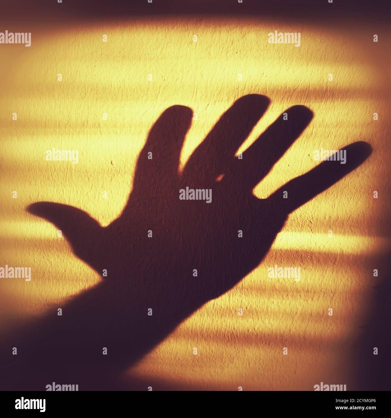 Shadow of a hand showing five fingers on a wall. Stock Photo