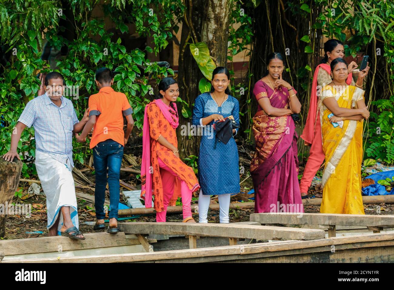 Man & women in colourful traditional clothing wait for ferry boat on