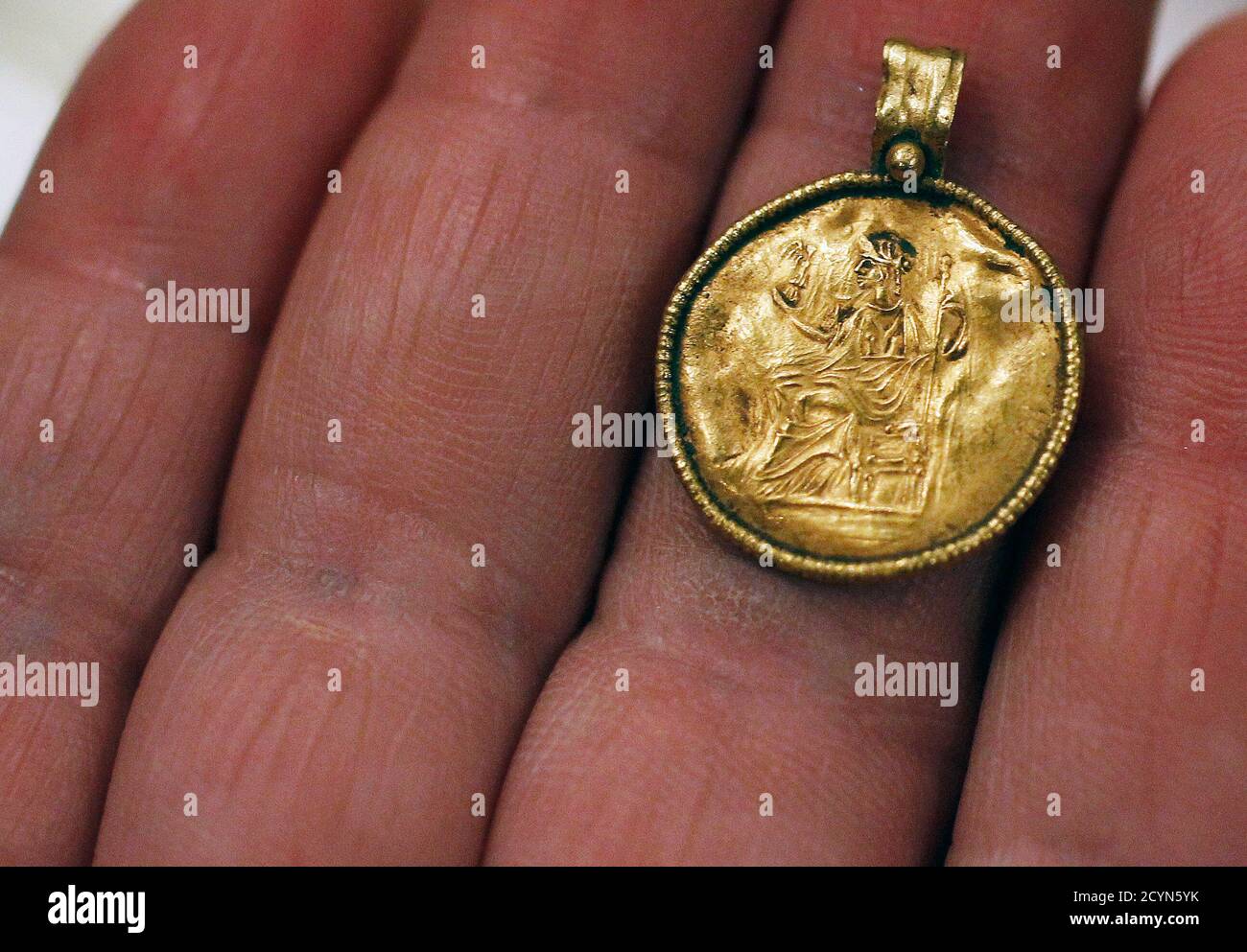 An expert at the National History Museum displays a pendant, bearing an  image of Nike, the Greek goddess of victory, along with other antique  artefacts during a news conference in Sofia June