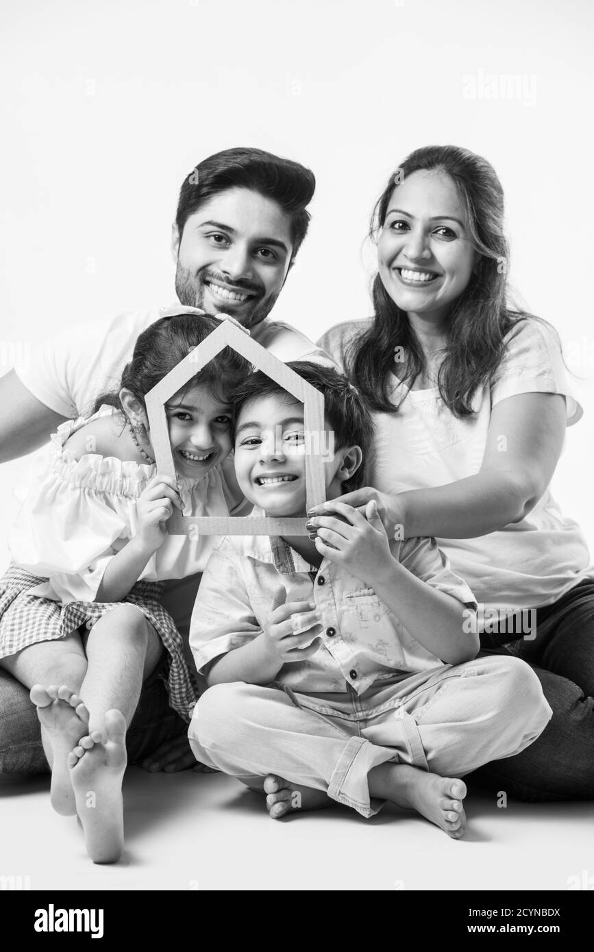 Indian family Father, mother, son and daughter holding 3D paper model of home - Real Istate Concept in India Stock Photo