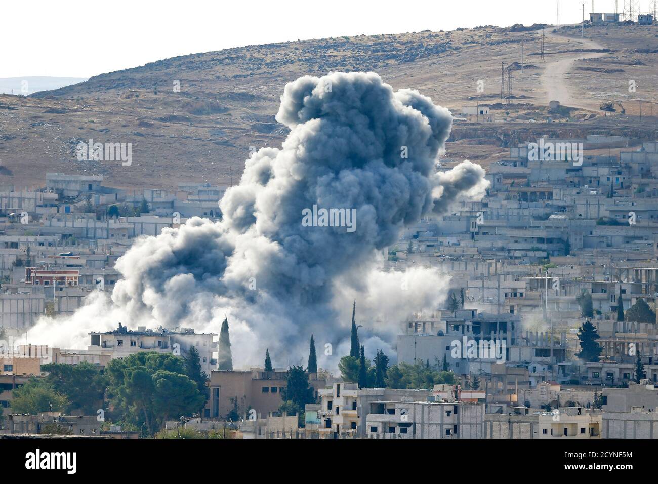 Smoke rises from the Syrian town of Kobani, seen from near the Mursitpinar border crossing on the Turkish-Syrian border in the southeastern town of Suruc in Sanliurfa province October 15, 2014. American-led forces conducted 21 airstrikes near Kobani, Syria, in the last two days to slow the advance of Islamic State militants, the U.S. military said on Tuesday, warning the situation on the ground is fluid as militants try to gain territory. REUTERS/Kai Pfaffenbach (TURKEY - Tags: MILITARY CONFLICT POLITICS) Stock Photo